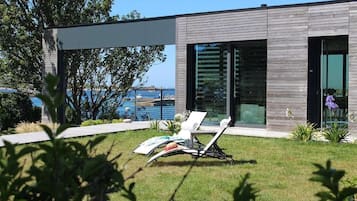 Une maison moderne avec une piscine, une pelouse et une chaise.