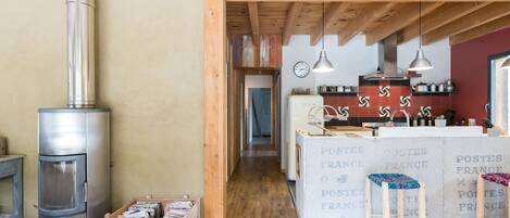 A rustic kitchen with wooden beams, a stainless steel stove, and a tiled backsplash with 'POSTES FRANCE' text.