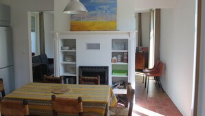 Un coin repas avec une table dressée pour quatre personnes, une cheminée et un tableau accroché au-dessus.