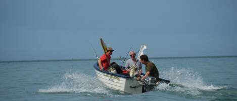 A small boat with three people on it, moving through calm water.