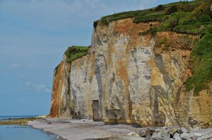 Eine Küstenklippe mit einem felsigen Strand und ein paar Spaziergängern.
