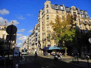 A street view with a row of multi-story buildings, a pedestrian crossing, and a bus stop.