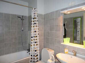 A bathroom with a shower, toilet, sink, and mirror.