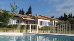 A poolside view of a house with a tiled roof and blue shutters, surrounded by a white fence. - villa, countryside, quiet, spacious (8 persons), secure swimming pool. (Sérignan-Du-Comtat)