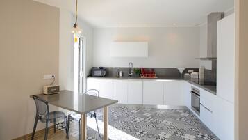 A modern kitchen with white cabinets, a black countertop, and a patterned floor.