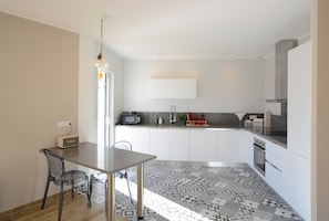 Una cucina moderna con mobili bianchi, un piano di lavoro nero e un pavimento decorato.