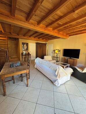 Ein gemütliches Wohnzimmer mit Holzboden, einer Couch, einem Fernseher und einem Schachbrett.