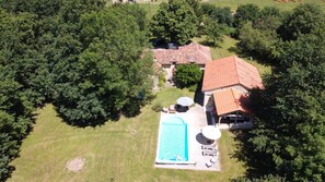 Eine Vogelperspektive eines Hauses mit Schwimmbad, umgeben von Bäumen und einer Rasenfläche.