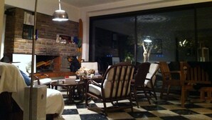 A cozy living room with a fireplace, wooden furniture, and a large window.