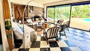 A living room with a checkered floor, a fireplace, and a view of a pool.