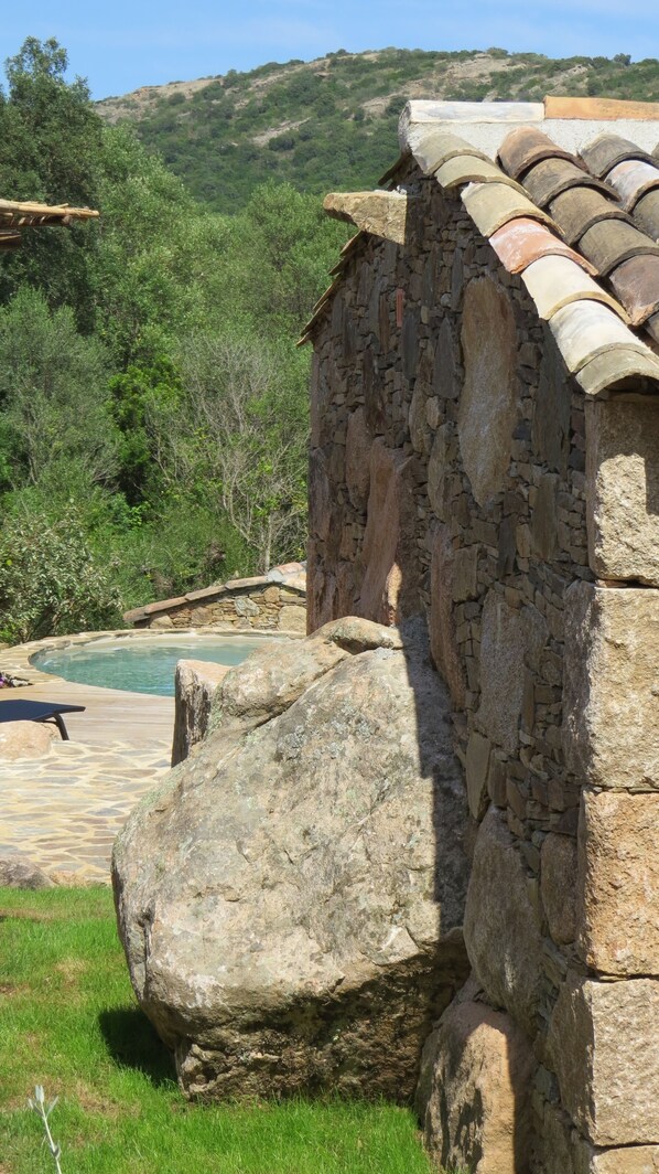 A stone building with a tiled roof, a stone wall, and a pool area. - 3 min from Palombaggia, Magnificent Corsican sheepfold with private pool and garden (Porto-Vecchio)