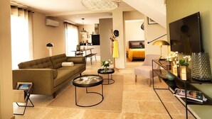 A modern living room with a sofa, coffee table, TV, and a dining area.