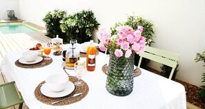 A table set for breakfast with a vase of flowers, a bottle of juice, and a glass of orange juice.
