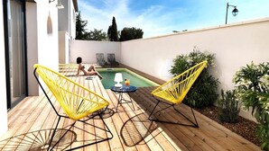 A wooden deck with yellow chairs and a pool.