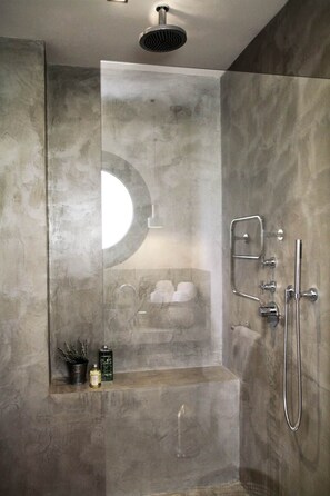 A modern shower with a rain showerhead, handheld shower, and a handheld toothbrush.