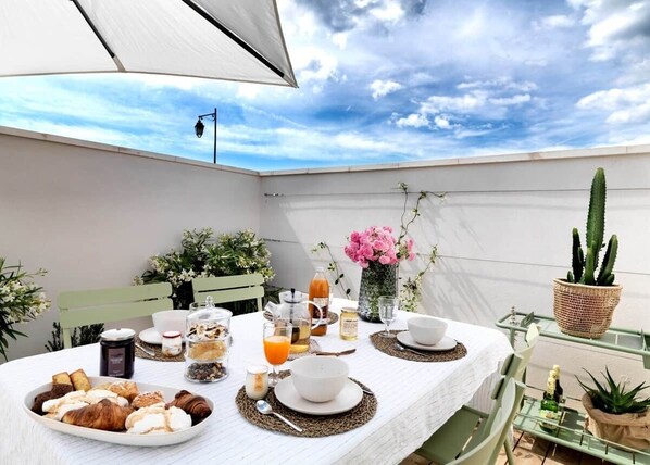 A table set for breakfast with pastries, drinks, and a cactus plant.