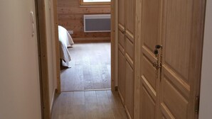 Un couloir au plancher de bois mène à une chambre à coucher qui contient un lit et une fenêtre.