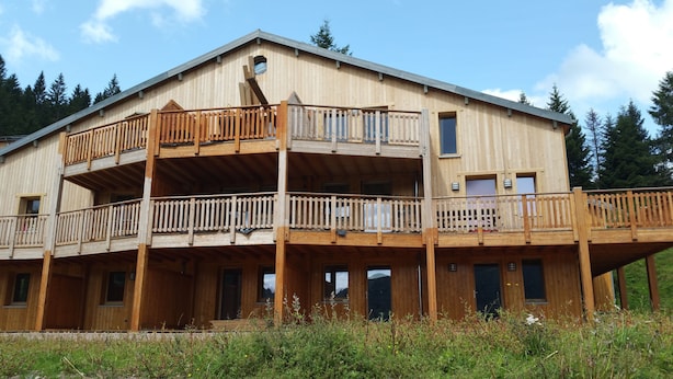 Un bâtiment en bois à deux étages, doté de balcons, de grandes fenêtres et d’un toit plat.