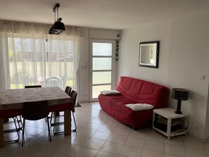 Un coin repas avec une table et des chaises, un canapé rouge, une lampe et un miroir au mur.