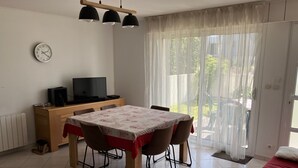A dining area with a table, chairs, a television, and a clock on the wall. - Apartment T3 in Larmor beach 5 minutes walk from the beaches (Larmor-Plage)