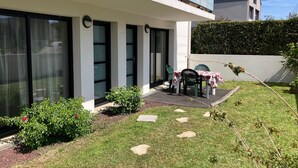 A modern house with a patio, a table with chairs, and a garden. - Apartment T3 in Larmor beach 5 minutes walk from the beaches (Larmor-Plage)