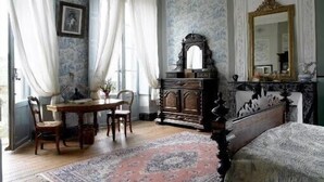 Ein Zimmer mit einem hölzernen Bett, einem Nachttisch, einem Tisch mit Stühlen und einem großen Spiegel.