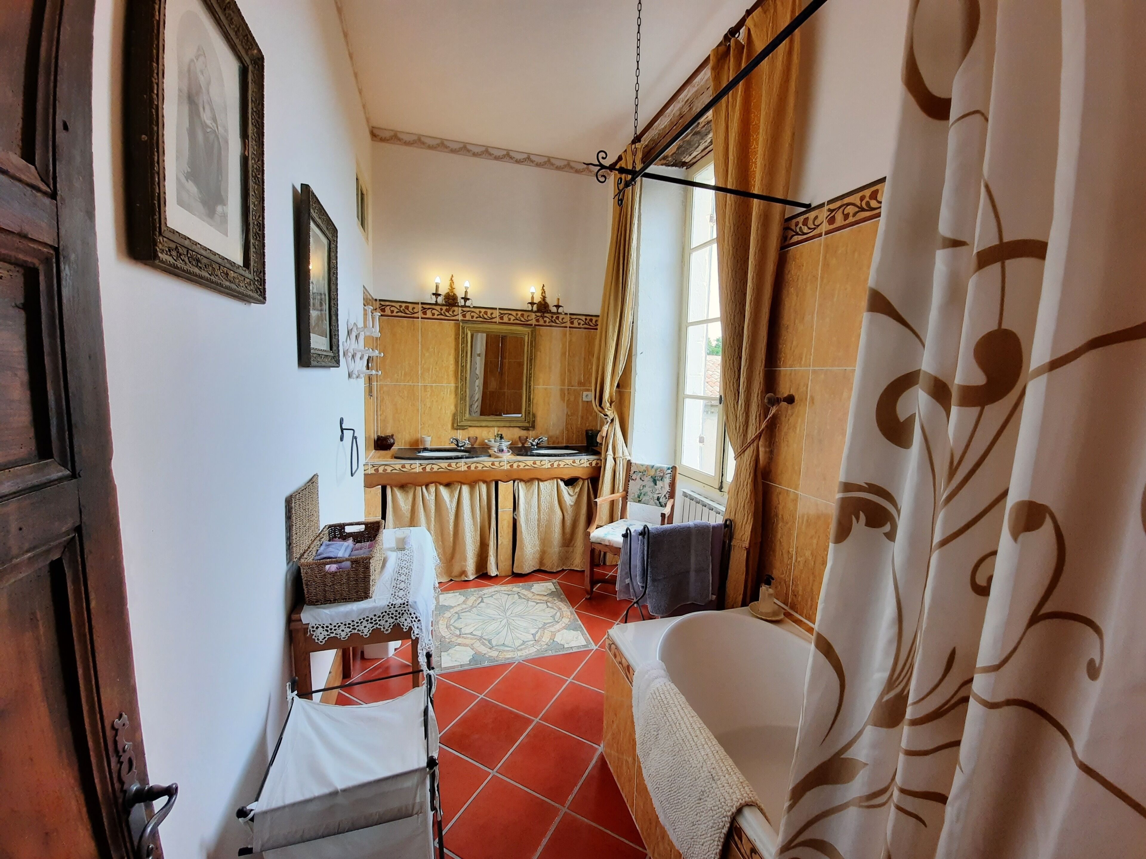 Een badkamer met een bad, een wastafel en een spiegel. Er staat een stoel en een tafeltje met handdoeken.