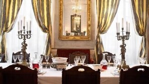 Ein formeller Speisesaal mit gedecktem Tisch für vier Personen, einer Kristallleuchtre und einem Spiegel an der Wand.