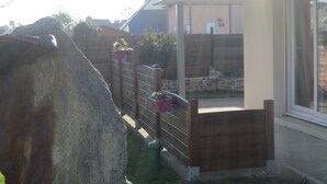 A residential property with a stone wall, wooden fence, and flower pots.