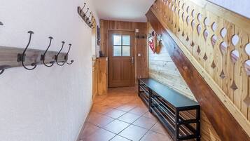 A hallway with a wooden bench, a door with a frosted glass window, and a wall-mounted coat rack.