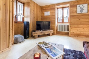 A cozy wooden cabin interior with a television, a fireplace, and a framed deer head artwork. - Chalet des Etoiles (11 people) Val-Cenis (Sollières-Sardières)