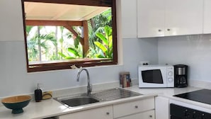 A compact kitchen with a washing machine, a sink, a microwave, and a stove. - GLIGLI FOR LOVERS (Sainte-Anne)