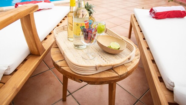 A poolside setting with lounge chairs, a wooden table with drinks, and a pool in the background. - GLIGLI FOR LOVERS (Sainte-Anne)
