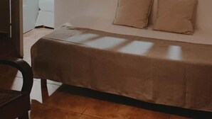 A room with a bed, a hanging light fixture, a window with blinds, and a door leading to another room. - GLIGLI FOR LOVERS (Sainte-Anne)