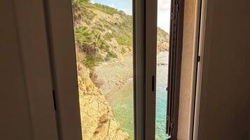 Une pièce avec une fenêtre donnant sur une côte rocheuse et un ciel dégagé.
