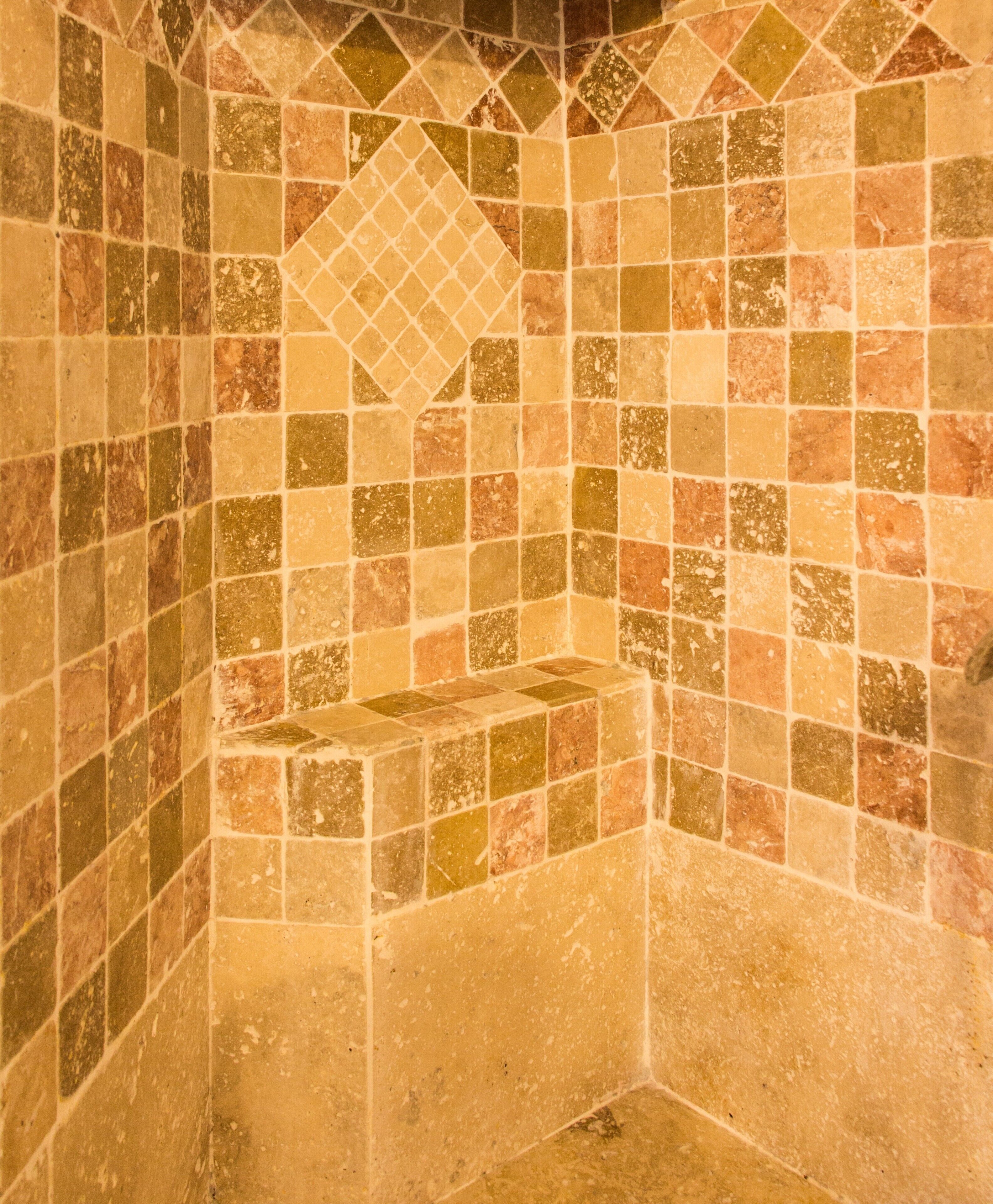 A bathroom with mosaic tile walls and a corner sink.