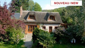 Une maison traditionnelle avec un toit de chaume, des fenêtres en bois et une façade en pierre.