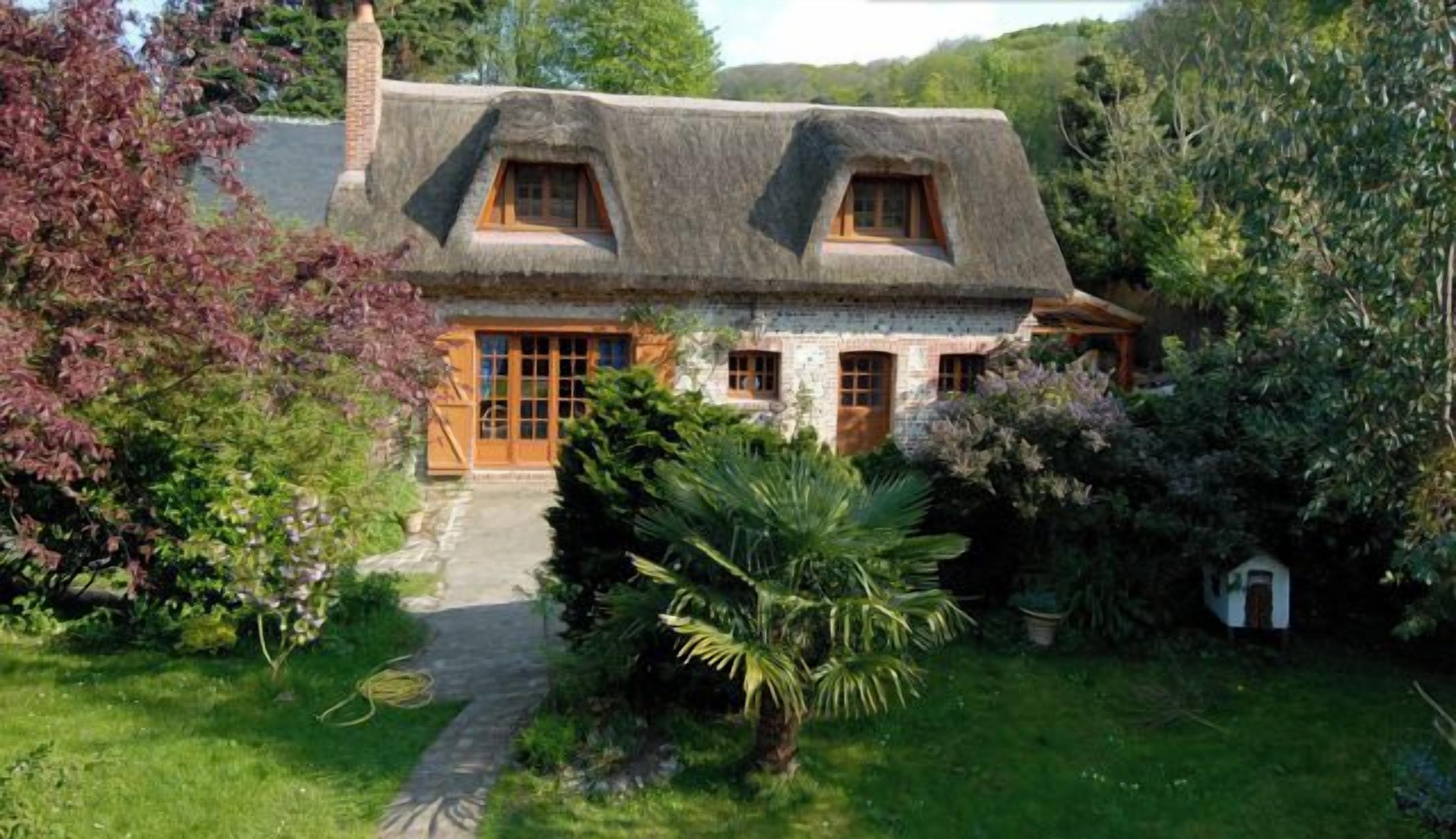 Une maison traditionnelle avec un toit de chaume, des fenêtres en bois et une façade en pierre.