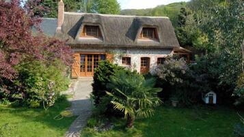 Une maison traditionnelle avec un toit de chaume, des fenêtres en bois et une façade en pierre.