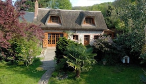 Une maison traditionnelle avec un toit de chaume, des fenêtres en bois et une façade en pierre.