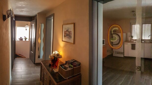 A hallway with a wooden cabinet, a vase with flowers, and a framed picture on the wall. - Gîte des 5 Saisons *** (Bernardswiller)
