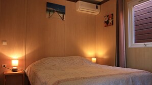 A bedroom with a bed, two bedside lamps, an air conditioning unit, and a window with blinds. - Chalet Filaos 2*, sea view, near Saint-Leu and its beaches  (Saint-Leu)