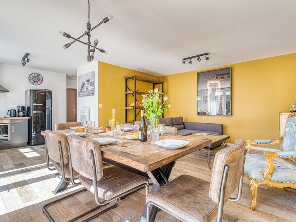 A dining area with a wooden table, chairs, and a vase of flowers.