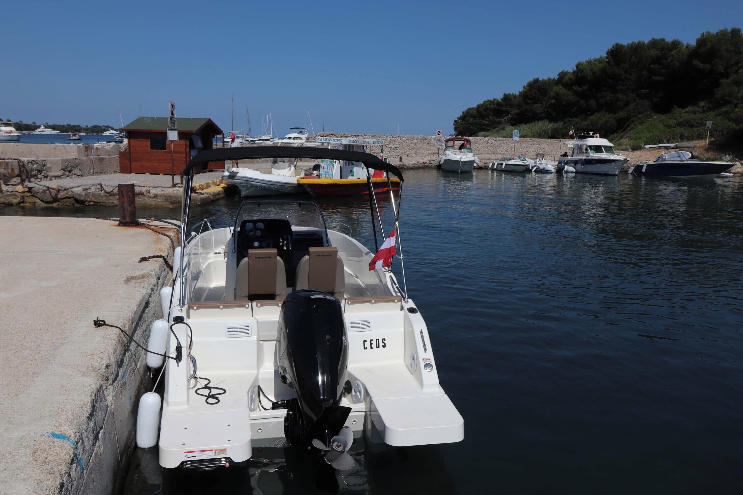 Un vaixell atracat al port esportiu, amb vista clara a l'aigua i altres embarcacions al fons.