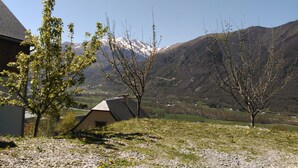 Un paysage rural avec une maison, un petit bâtiment et des montagnes en arrière-plan.