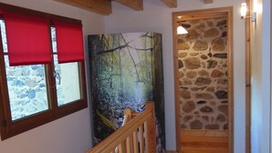 A wooden staircase with a red carpet, a stone wall, and a forest mural.
