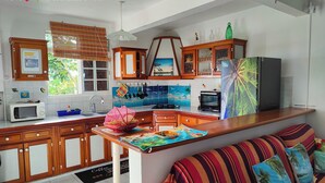 A modern kitchen with wooden cabinets, a microwave, and a large island. - CHEZ LUKETO VIEUX -HABITANTS  (Vieux Habitants)