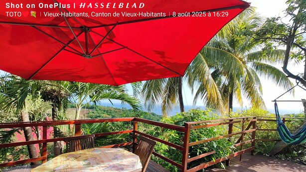 A wooden deck with a table and chairs, a red umbrella, and a hammock. - CHEZ LUKETO VIEUX -HABITANTS  (Vieux Habitants)