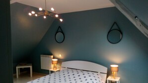Ein Schlafzimmer mit einem Bett, zwei Nachttischen mit Lampen, einem Heizkörper und einer Deckenleuchte.