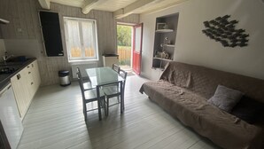Ein kompakter Wohnraum mit Küchenzeile, Esstisch und Sofa.